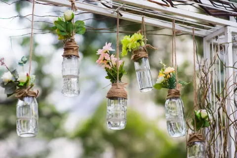 Upcycling ideen gartendeko selber machen: Hängende Glasflaschen mit Blumen als romantische Deko.
