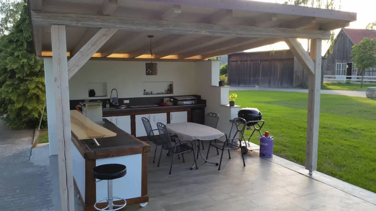 Gemütlicher **Grillplatz im Garten** mit überdachter Außenküche, Bartresen, Esstisch und Grill. Perfekt für gesellige Abende.