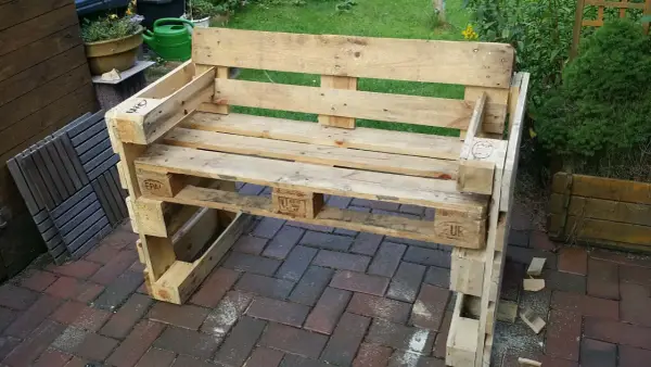 Ein selbstgebautes Palettensofa steht auf einer Terrasse. Die Sitzfläche und Rückenlehne sind aus Holzpaletten gefertigt.
