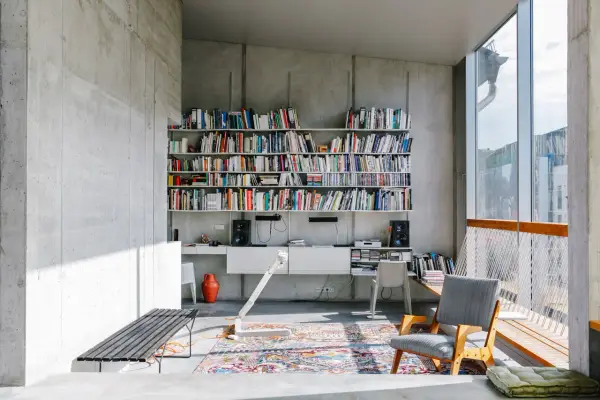 Ein bunter, detailreicher Perserteppich bildet einen warmen Kontrast zur kühlen Betonarchitektur und zeigt, wie man einen Perserteppich modern kombinieren kann.